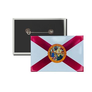 May include: A red, white, and blue button featuring the state flag of Florida. The flag has a diagonal red cross on a white background with the state seal in the center. The seal features a depiction of the state tree, the sabal palm, and the words "Great Seal of the State of Florida" and "In God We Trust".