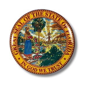Puede incluir: Un botón redondo con el Gran Sello del Estado de Florida. El sello tiene un borde amarillo con el texto "GREAT SEAL OF THE STATE OF FLORIDA" y "IN GOD WE TRUST". El centro representa a una mujer nativa americana y un velero.