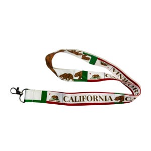 Könnte beinhalten: Ein weißes Lanyard mit einem rot-grün-weißen Design der Flagge des Bundesstaates Kalifornien. Das Lanyard zeigt ein sich wiederholendes Muster des kalifornischen Bären und die Worte "California Republic" und "California".