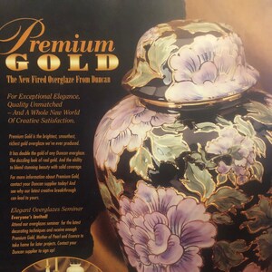 Puede incluir: Un tarro de cerámica negro y dorado con un diseño floral. El tarro tiene una tapa con un diseño floral. El texto "Premium Gold" está escrito en letras doradas sobre un fondo negro. El texto "The New Fired Overglaze From Duncan" está escrito en letras blancas sobre un fondo negro.