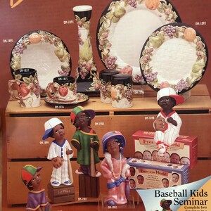 Może przedstawiać: Zestaw ceramicznych figurek przedstawiających graczy w baseball. Figurki są pomalowane w różnych kolorach, w tym niebieskim, czerwonym, zielonym i różowym. Figurki są ubrane w uniformy baseballowe i trzymają kije baseballowe lub rękawice. Figurki są ustawione na drewnianej półce z tabliczką z napisem "Baseball Kids Seminar".