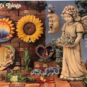 Puede incluir: Una colección de artículos de decoración de jardín, que incluyen un ángel de cerámica que sostiene una cesta de flores, una rana con un gorro de bufón, un termómetro en forma de corazón, un girasol, una pajarera en forma de luna y un par de dragones. Los artículos están dispuestos sobre un fondo de ladrillo con hiedra verde.