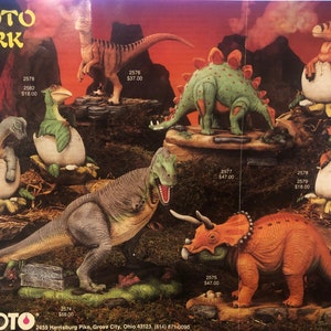 May include: A collection of ceramic dinosaur figurines, including a green stegosaurus, a brown triceratops, a gray T-Rex, and several baby dinosaurs in eggs. The figurines are painted in realistic colors and have detailed features. The image also includes the text "SCIOTO PARK" and a phone number.