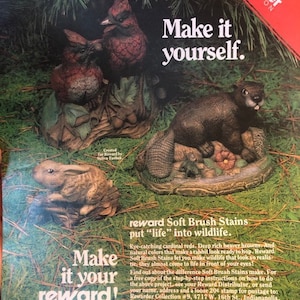 Puede incluir: Un anuncio vintage para las pinturas Soft Brush Stains de Reward, un producto de pintura para cerámica. El anuncio presenta un cardenal, un castor y un conejo de cerámica pintados, con el texto "Hazlo tú mismo." y "Las pinturas Soft Brush Stains de Reward dan vida a la vida silvestre."