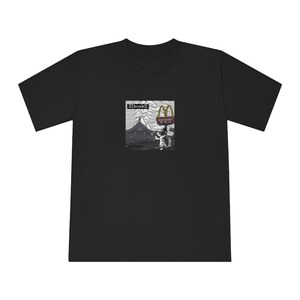 Puede incluir: Camiseta negra con un gráfico de un paisaje de montaña y un cartel de McDonald's. El texto "Decode" está impreso en el cartel.