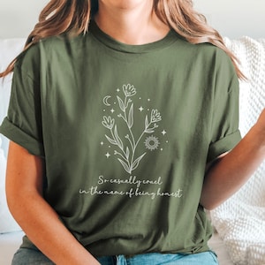 May include: A green t-shirt with a white floral design and the text "So casually cruel in the name of being honest".