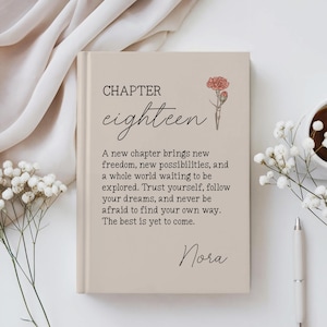 May include: A beige hardcover book featuring the text "CHAPTER eighteen" and a small illustration of a pink carnation. Below, the text reads: "A new chapter brings new freedom, new possibilities, and a whole world waiting to be explored. Trust yourself, follow your dreams, and never be afraid to find your own way. The best is yet to come." The name "Nora" is printed at the bottom.