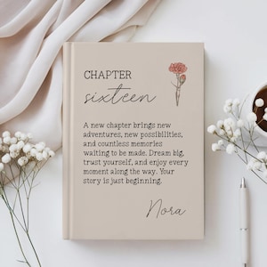 Puede incluir: Un libro de tapa dura de color beige con el texto CHAPTER sixteen, una pequeña ilustración de un clavel rosa y el nombre Nora. El texto impreso dice: A new chapter brings new adventures, new possibilities, and countless memories waiting to be made.