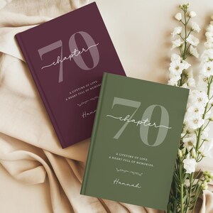 May include: Two hardcover books with matte covers in deep burgundy and olive green. The front covers feature the large number 70, the word chapter in script, and the text A LIFETIME OF LOVE, A HEART FULL OF MEMORIES, and the name Hannah.