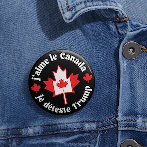 Puede incluir: Un botón blanco y negro con una bandera canadiense y el texto "j'aime le Canada je déteste Trump".