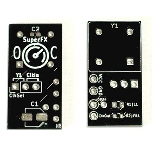 Pode incluir: Duas placas de circuito impresso retangulares pretas com marcações de serigrafia brancas. A placa esquerda apresenta o texto SuperFX, C2, C1, Y1, ClkIn e ClkSel. A placa direita exibe as etiquetas Y1, VCC, GND, ClkIn, ClkOut, R1, L1, R2 e FB1.