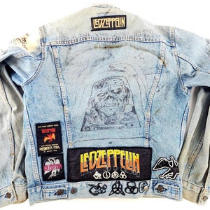 May include: Light blue denim jacket featuring multiple patches and a large illustration on the back. Patches include the band name "Led Zeppelin" and concert details. The jacket has a classic button-up design.