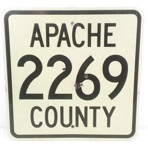 May include: White metal sign with black text and numbers. The sign reads "Apache 2269 County".