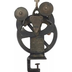 May include: Antique Universal Tarpen String Winder with a black metal base and a clamp. The winder has two wheels and a lever. The text "Universal Tarpen String Winder" is visible on the base.
