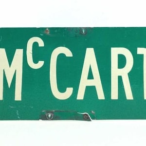 May include: A green street sign with white lettering that reads "W. MCCARTY STREET".
