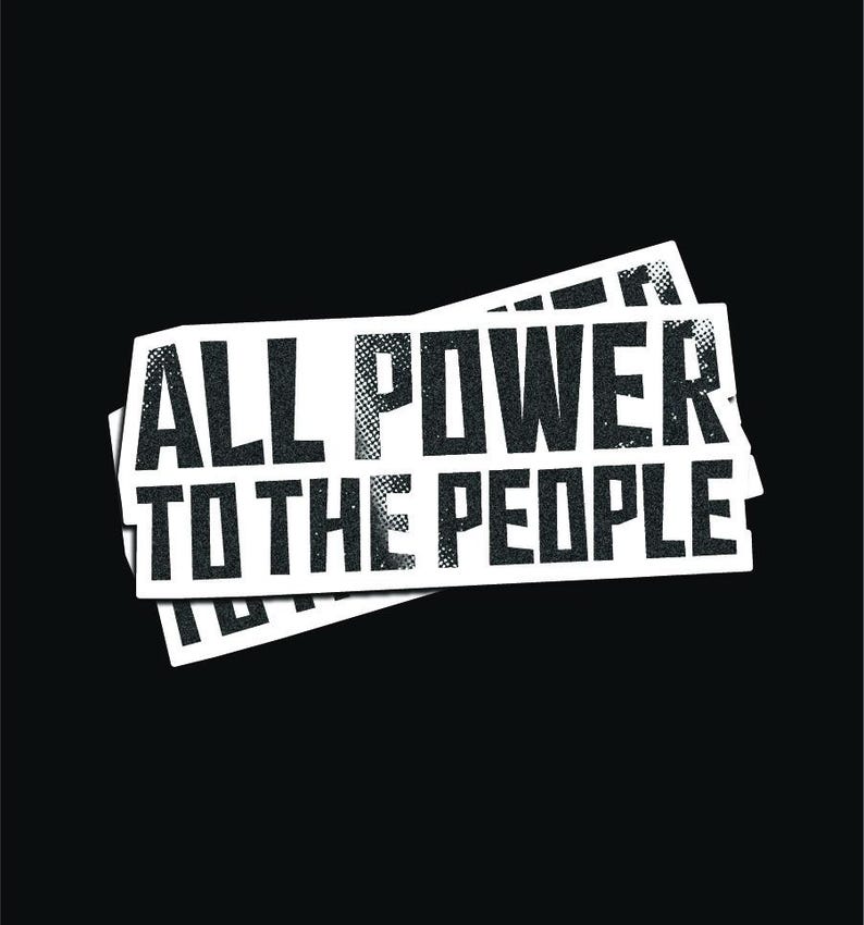 May include: A white sticker with black text that reads "ALL POWER TO THE PEOPLE". The sticker is slightly crumpled and has a distressed look.
