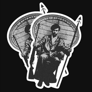 May include: Black and white illustration of a person sitting in a wicker chair holding a rifle. The person is wearing a jacket and has a serious expression on their face. The image is surrounded by a white border.
