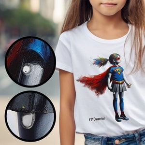 May include: White t-shirt with a colorful graphic of a superhero girl wearing a cape and holding a syringe. The text '#T1Dwarrior' is printed on the bottom of the shirt.