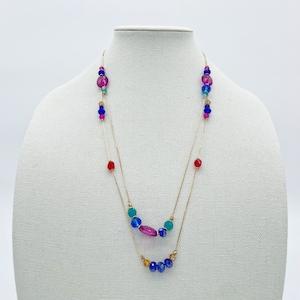 May include: A gold chain necklace with two strands of beads. The beads are in shades of blue, green, pink, and red.