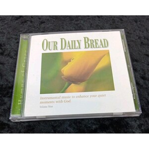 Puede incluir: Una caja de CD con el título "Our Daily Bread" en texto verde. La portada presenta un primer plano de una flor amarilla sobre un fondo verde. El texto de abajo dice "Música instrumental para mejorar tus momentos tranquilos con Dios."
