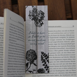 Könnte beinhalten: Ein schwarz-weißes Lesezeichen mit einem floralen Design und dem Text "I hate it here so I will go to secret gardens in my mind".