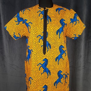 May include: A short-sleeved shirt with a bright yellow background and a repeating pattern of blue horses. The shirt has a black zip down the front and a round collar. The fabric has a small, dark pattern throughout.