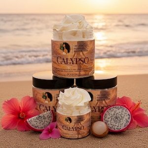 May include: Several jars of "CALYPSO" organic whipped body butter with white whipped cream on top, arranged on a sandy beach. The jars have a brown label with text and a woman's silhouette. Pink hibiscus flowers and sliced dragon fruit are also present.