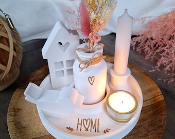 May include: A white decorative tray with a house, bird, and vase arrangement. The vase holds dried flowers and is tied with twine. A candle and a small glass candle holder are also on the tray. The word "HOME" is printed on the tray.