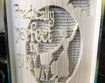 Può includere: Un libro con le pagine piegate per creare una scultura 3D di un drago. Il drago è bianco e il libro è bianco con una rilegatura verde. Il testo "Practically Perfect in Every Way" è visibile sul libro.