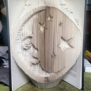 May include: A book folded into a three-dimensional sculpture of a bird. The sculpture is made from the pages of a book, and the pages are folded and layered to create the shape of the bird.