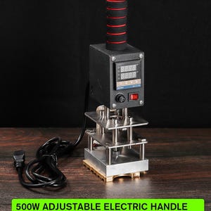 May include: A 500W adjustable electric handle for stamps under 6 inches. The device has a black body with a red and black handle. It features a digital display and a red power switch. A black power cord is connected to the device.
