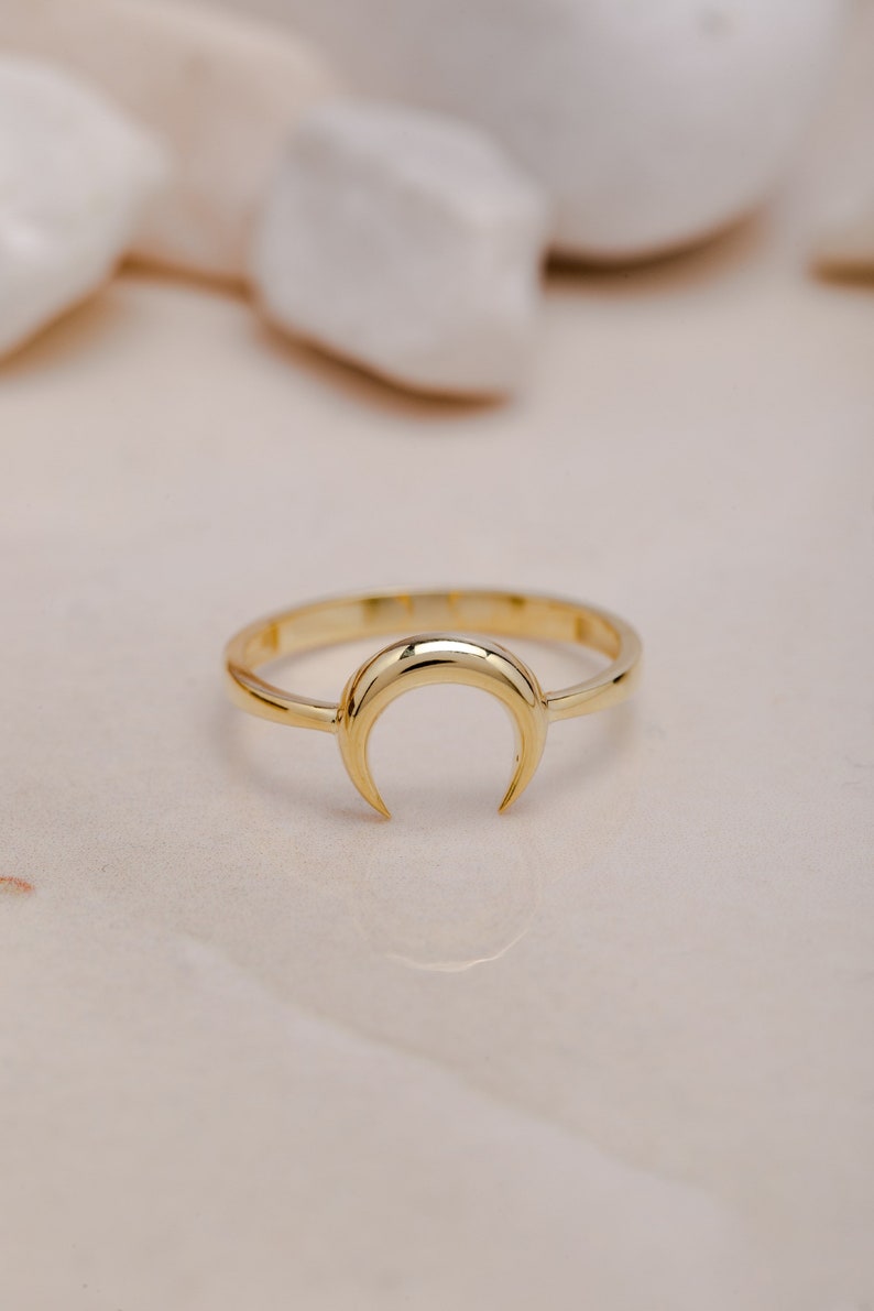 Elegant gold crescent moon ring on a light background