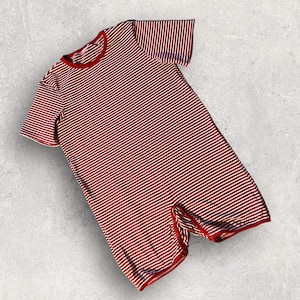 May include: Red and white striped short-sleeved jumpsuit with a crew neck.