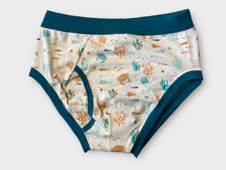 May include: White underwear with a teal blue waistband and a sea life print featuring fish, jellyfish, crabs, and coral.
