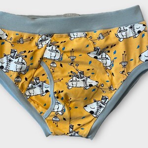 May include: Yellow underwear with a blue waistband and a repeating pattern of black and white illustrations of a dog wearing a hat and scarf.