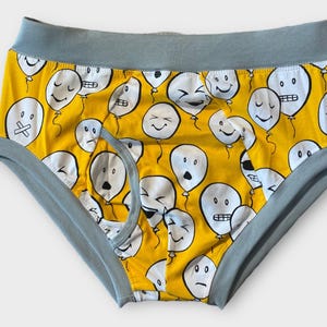 May include: Yellow underwear with a blue waistband and a pattern of white balloons with different facial expressions.
