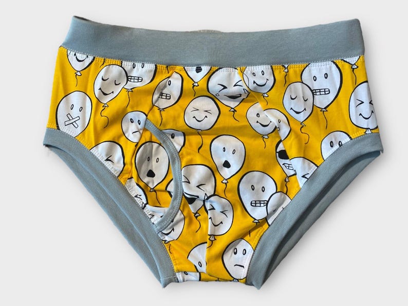 May include: Yellow underwear with a blue waistband and a pattern of white balloons with different facial expressions.
