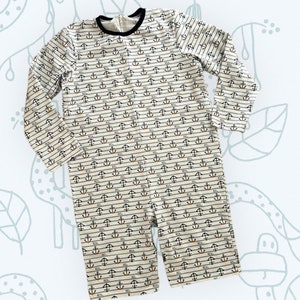 May include: A white long-sleeved onesie with black and orange anchor print. The onesie has a striped pattern and a crew neck.
