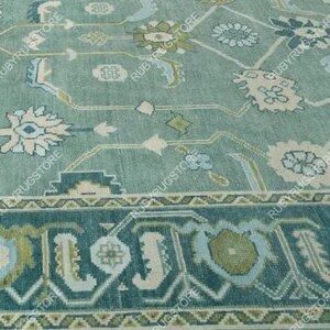 May include: A teal blue rug with a floral pattern in shades of white, pink, and green. The rug has a border with a geometric design.
