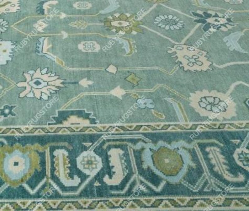 May include: A teal blue rug with a floral pattern in shades of white, pink, and green. The rug has a border with a geometric design.