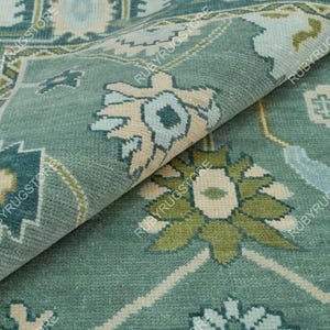May include: A teal blue rug with a floral pattern in shades of cream, green, and blue. The rug has a traditional Persian design.