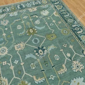 May include: A teal blue rug with a traditional Persian design. The rug has a light blue and cream colored floral pattern with a teal blue border.