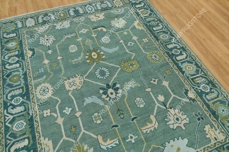 May include: A teal blue rug with a traditional Persian design. The rug has a light blue and cream colored floral pattern with a teal blue border.