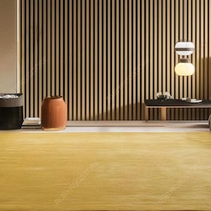 May include: A modern bedroom featuring a large, mustard-yellow rug. The room has a wooden slatted wall, a bed with a gray headboard, and a side table. A decorative vase and a trash can are also visible, creating a warm and inviting atmosphere.