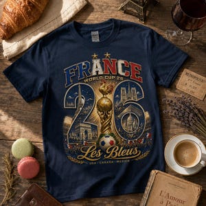 Puede incluir: Camiseta azul marino con un gr&aacute;fico que celebra la Copa del Mundo 26 de Francia. El dise&ntilde;o incluye la Torre Eiffel, un bal&oacute;n de f&uacute;tbol y el texto "FRANCE WORLD CUP 26" y "Les Bleus".