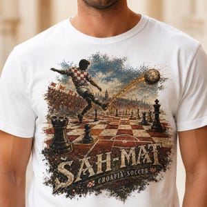 May include: A white t-shirt featuring a graphic print of a soccer player in a red and white checkered jersey kicking a soccer ball across a chessboard. The text "&Scaron;AH-MAT" and "CROATIA SOCCER" is printed below the chessboard in a distressed font.