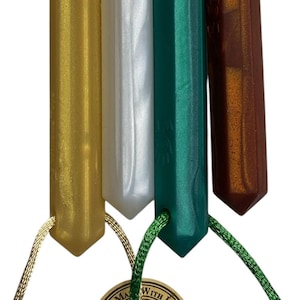 May include: Four gemstone pendants in gold, white, teal, and brown, each with a faceted, elongated shape. The pendants are suspended from cords of varying colors. A small tag with the words "thank you" is attached.