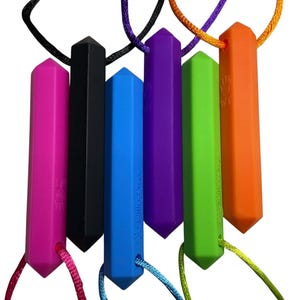 May include: A collection of six colorful, geometric-shaped chewable necklaces. The necklaces are in shades of pink, black, blue, purple, green, and orange. Each pendant is suspended from a matching or complementary colored cord. The brand name "Willow Toys" is printed on some of the pendants.