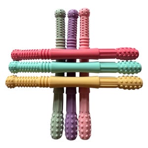 May include: A collection of colorful baby teething toys in shades of pink, green, purple, and yellow. Each toy has a textured design on the ends and a smooth center section. The toys are arranged in a cross-like pattern.