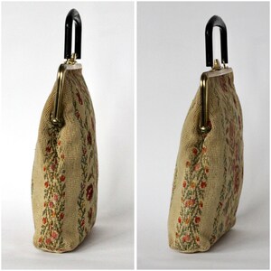 May include: A vintage beige handbag with a black handle and gold-toned clasp. The bag features a floral needlepoint design in red, green, and orange. The bag's shape is rectangular with a curved top.